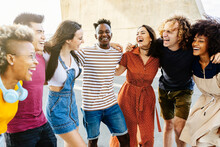 Group Of Happy Multiracial People Having Fun Together Outdoor - Smiling Young Adult Friends Laughing And Hugging Each Other In The Street. Happiness, Friendship And Summer Holidays Concept - Focus On