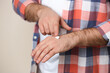 Man applying cream onto hand on beige background, closeup