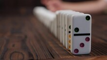 Close-up Of A Domino Falling On A Table, Blurred Background. The Domino Effect.