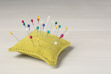 Yellow Cushion With Pins On White Table. Space For Text