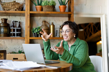 Smiling senior woman filling forms online in home interior. Online working from home.