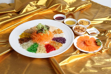 chinese new year colourful lo hei yu sheng with smoked salmon, vegetables and sauces in white gold background asian halal menu for cny festival