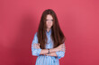 Little kid girl 13 years old in blue dress isolated on pink background look to camera with angry gaze crossed arms
