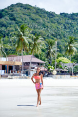 Wall Mural - Sexy girl in red swimsuit posing at the tropical beach