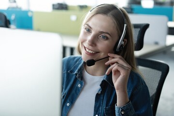 Wall Mural - How can I help you? Beautiful call center workers in headphones are working at modern office