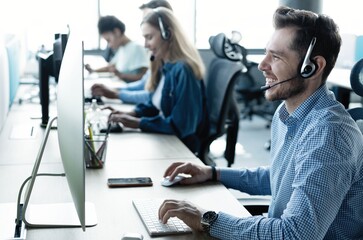 Wall Mural - Young handsome male customer support phone operator with headset working in call center