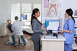 © DC Studio - Patients in stomatology reception waiting in line taking filling form, doctor examining senior man discussing teeh healthcare. Stomatology corridor with people waiting consultation.