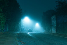 An Dark Mysterious Eerie, English Road With Street Lights On An Atmospheric Foggy Winters Night. UK