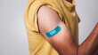 © Phushutter - bi-colored Asian man showing vaccinated arm with adhesive patch after getting Covid-19 vaccine injection.