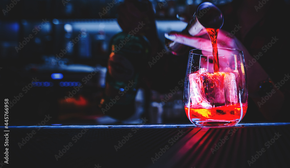 Closeup shot of bartender hand making negroni cocktail. Negroni classic cocktail and gin short drink with sweet vermouth, red bitter liqueur and dried orange garnish. - obrazy, fototapety, plakaty 