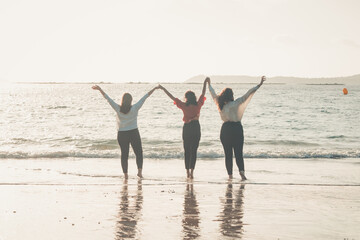 Happy women friends runs at sea beach during a bright day, friends happy relax having fun playing on beach near sea when sunset in evening.