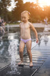 A little girl bathes under the streams of a fountain