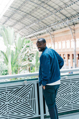 afro american young stylish man standing in station with mobile phone