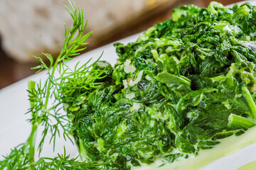 Wall Mural - Cooked spinach with garlic on a white plate. Vegetarian food.