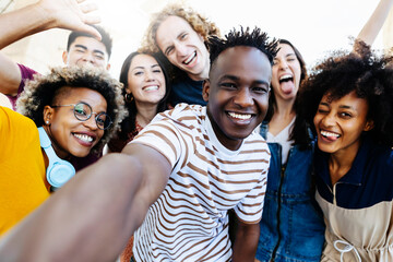 Group of multiracial happy best friends taking selfie photo with smartphone camera - Cheerful young hipster people from different cultures and races having fun together outdoor - Friendship, student