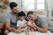 © godji10 - A couple gay parent playing with adopted child in bedroom