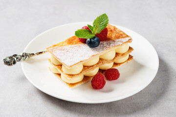 Classic french dessert millefeuille with vanilla cream and fresh berries.