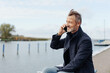 © contrastwerkstatt - Attractive middle-aged man chatting on a mobile at the seaside