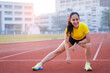 © EduLife Photos - A young beautiful Asian woman in sports outfits doing stretching before workout outdoor in the city stadium  in the morning to get a healthy lifestyle. Healthy young woman doing excercise
