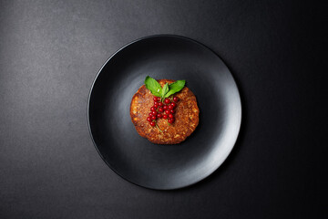 Vegan homemade pancake with red currants on plate, on black background.