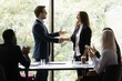 Business team leader congratulating employee on hiring, promotion, high work result, expressing recognition. Businessman shaking hands with female employee. Group applauding coworker success.