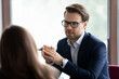 © fizkes - Serious male manager, lawyer, broker, talking to client, giving consultation, advice. Businessman, employer interviewing job candidate for hiring. Business leader in glasses meeting with employee