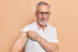 © WHstudio Leushin N - Grey haired male pensioner shows plastered arm got vaccinated to reduce risk of catching or spreading coronavirus waits for side effects wears transparent glasses and t shirt poses indoor in clinic