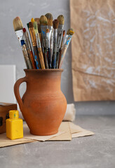 Sticker - Paint brush in clay jug and art painter tool on table background texture. Paintbrush for painting