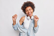 © wayhome.studio  - Horizontal shot of carefree African American woman dances with rhythm of musoc closes eyes from pleasure moves actively catches every bit of song dressed in denim jacket headphones around neck