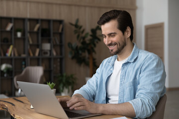 Wall Mural - happy millennial businessman working on online project on computer, analyzing sales statistics, feel