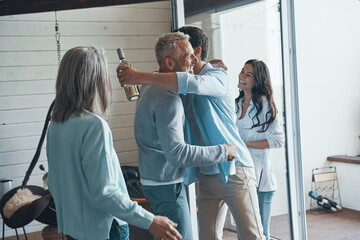 Happy senior parents meeting young couple inside the house