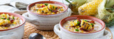 Fototapeta  - Narrow view of three bowls of chicken and corn chowder topped with grilled corn and bacon, ready for eating.