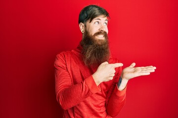 Sticker - Redhead man with long beard pointing open palm with finger smiling looking to the side and staring away thinking.