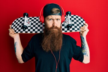 Poster - Redhead man with long beard holding skate wearing headphones skeptic and nervous, frowning upset because of problem. negative person.