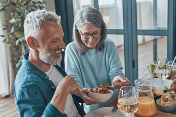 Wall Mural - Happy senior couple communicating and smiling while having dinner together