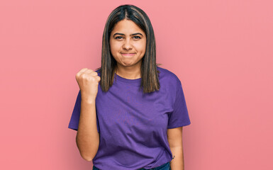 Poster - Young hispanic girl wearing casual purple t shirt angry and mad raising fist frustrated and furious while shouting with anger. rage and aggressive concept.