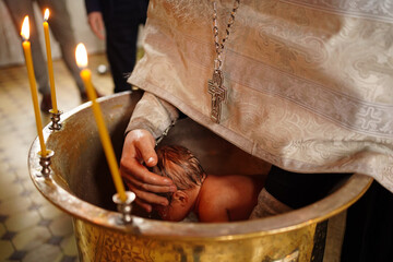 Poster - the baby is lowered into the font at the baptism in the church. 