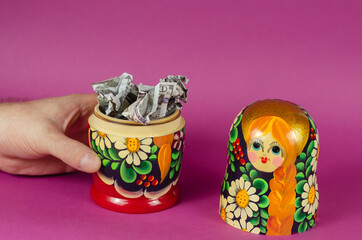 Hand holds Russian matryoshka full of money.