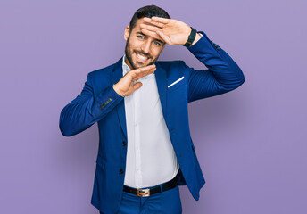 Canvas Print - Young hispanic man wearing business jacket smiling cheerful playing peek a boo with hands showing face. surprised and exited