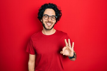 Canvas Print - Handsome hispanic man wearing casual t shirt and glasses showing and pointing up with fingers number three while smiling confident and happy.