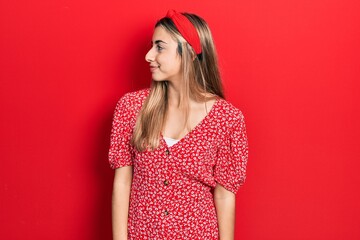 Poster - Beautiful hispanic woman wearing summer dress looking to side, relax profile pose with natural face with confident smile.