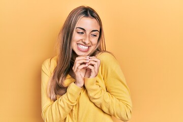 Poster - Beautiful hispanic woman wearing casual yellow sweater laughing nervous and excited with hands on chin looking to the side