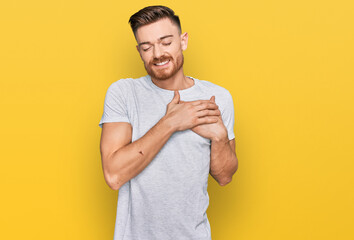 Wall Mural - Young redhead man wearing casual grey t shirt smiling with hands on chest with closed eyes and grateful gesture on face. health concept.