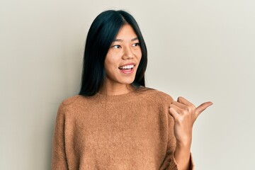 Sticker - Young chinese woman wearing casual clothes pointing thumb up to the side smiling happy with open mouth