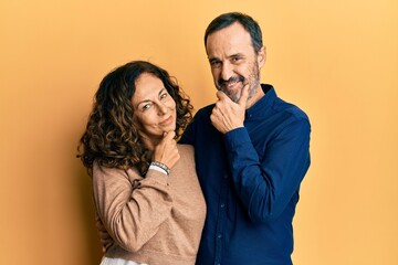 Sticker - Middle age hispanic couple wearing casual clothes looking confident at the camera smiling with crossed arms and hand raised on chin. thinking positive.