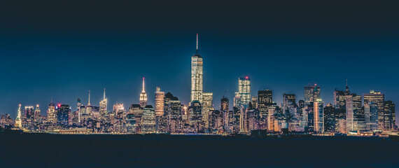 Fototapete - New York City Manhattan downtown skyline at dusk with skyscrapers illuminated over Hudson River panorama.