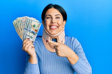 Poster - Beautiful brunette woman wearing cervical collar holding insurance money smiling happy pointing with hand and finger