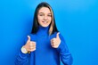 Young brunette girl wearing turtleneck sweater success sign doing positive gesture with hand, thumbs up smiling and happy. cheerful expression and winner gesture.