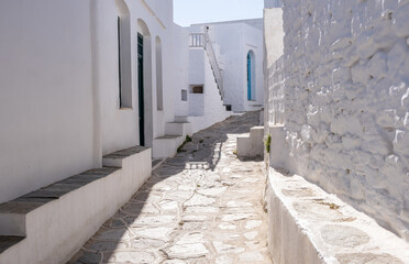 Wall Mural - Sifnos island, Cyclades Greece. Whitewashed buildings empty narrow cobblestone alley.