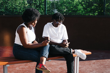 two happy African-American women communicate and laugh on the street in the summer